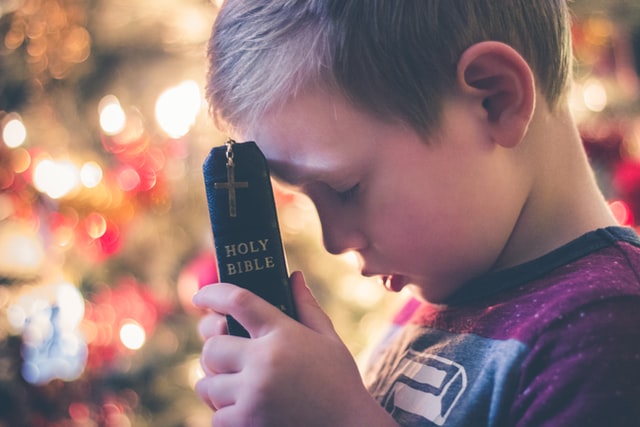 Picture boy praying with Bible